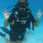 buceo con botella haciendo la señal de todo bien en las aguas transparentes y cristalinas de las islas maldivas en una laguna de fondo arenoso