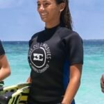 buceo con botella en las islas maldivas neopreno saliendo del agua con aletas de buceo en la mano océano de fondo y azul cielo