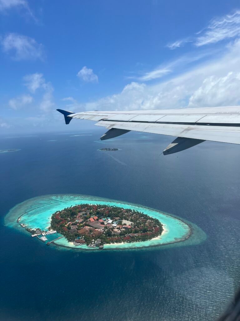 foto desde el avión llegando a Maldivas de una isla local donde se pueden ver sus colores azules vibrantes y variados.